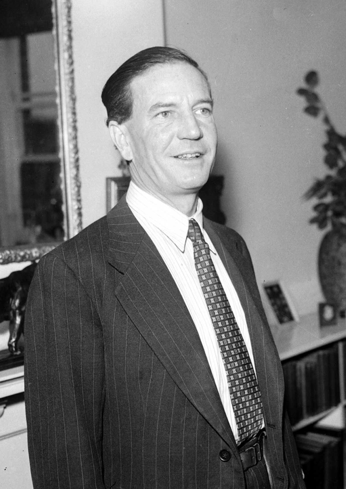 Photograph of a slightly smiling middle-aged man in a suit and tie.